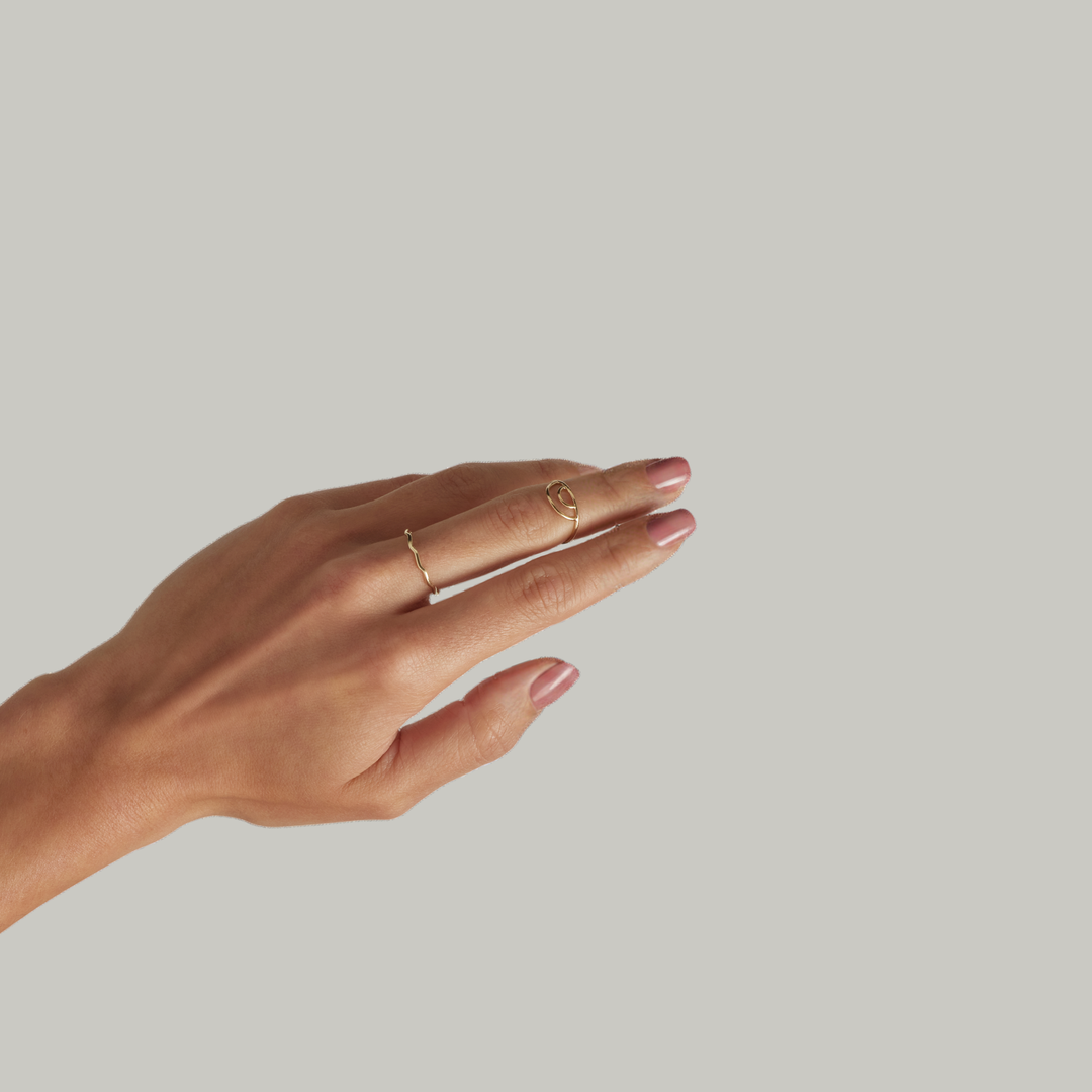 Woman wearing gold filled stacking rings, thin minimalist bands layered on fingers