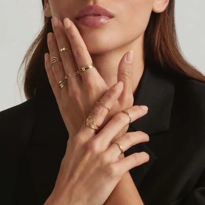 Close up of woman's hand wearing multiple 14K gold filled stacking rings - demi-fine jewellery by Margot Georgia