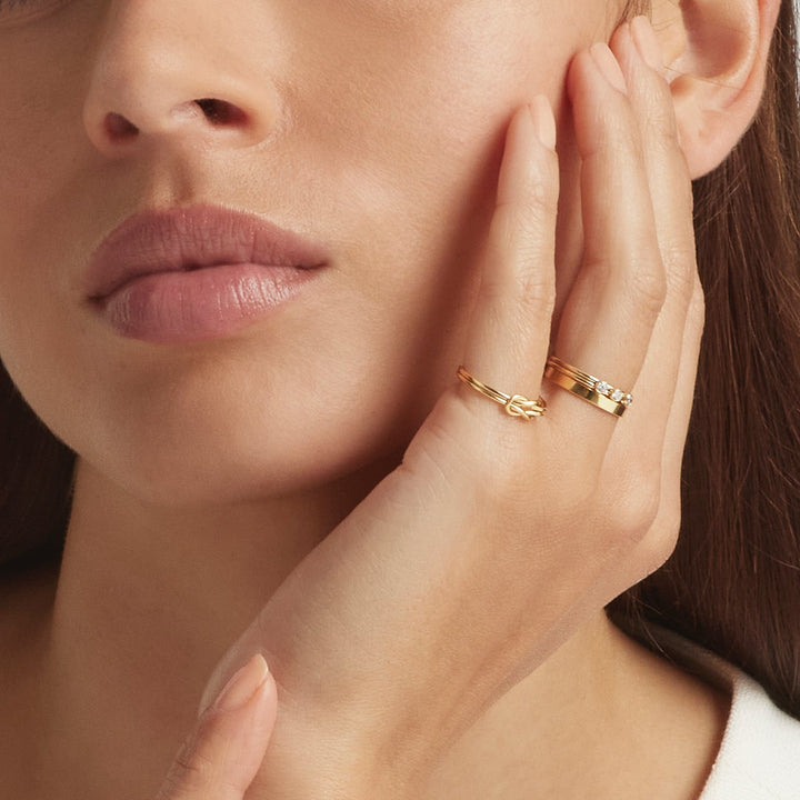Close-up of a woman wearing 14K gold filled stacking rings: Tressa, Ellis and Double Knot - demi-fine jewellery by Margot Georgia