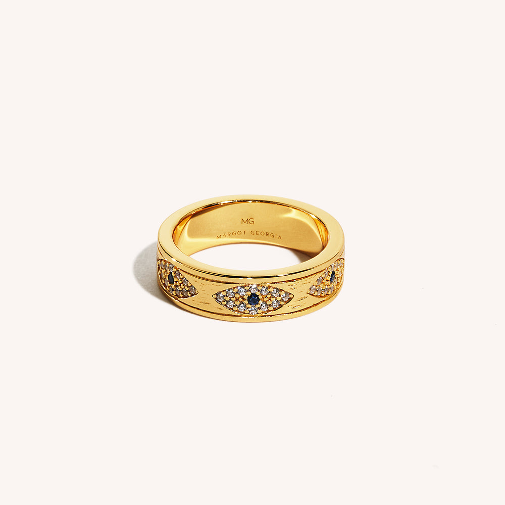 An 18K gold band ring with intricate design featuring sapphire and white cubic zirconia stones, stamped with 925 sterling silver.