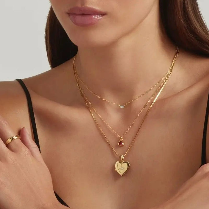 A woman wearing 18K Gold Vermeil Heart Locket, Genessa Trine Birthstone and Baguette Bar necklaces and the stargazing ring - demi-fine jewellery by Margot Georgia