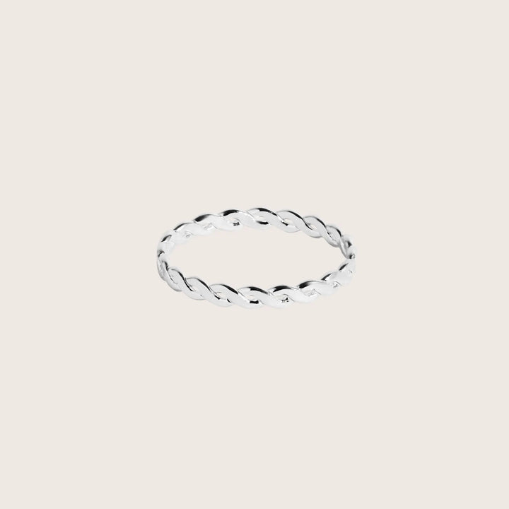 Silver ring with a twisted design on a light beige background