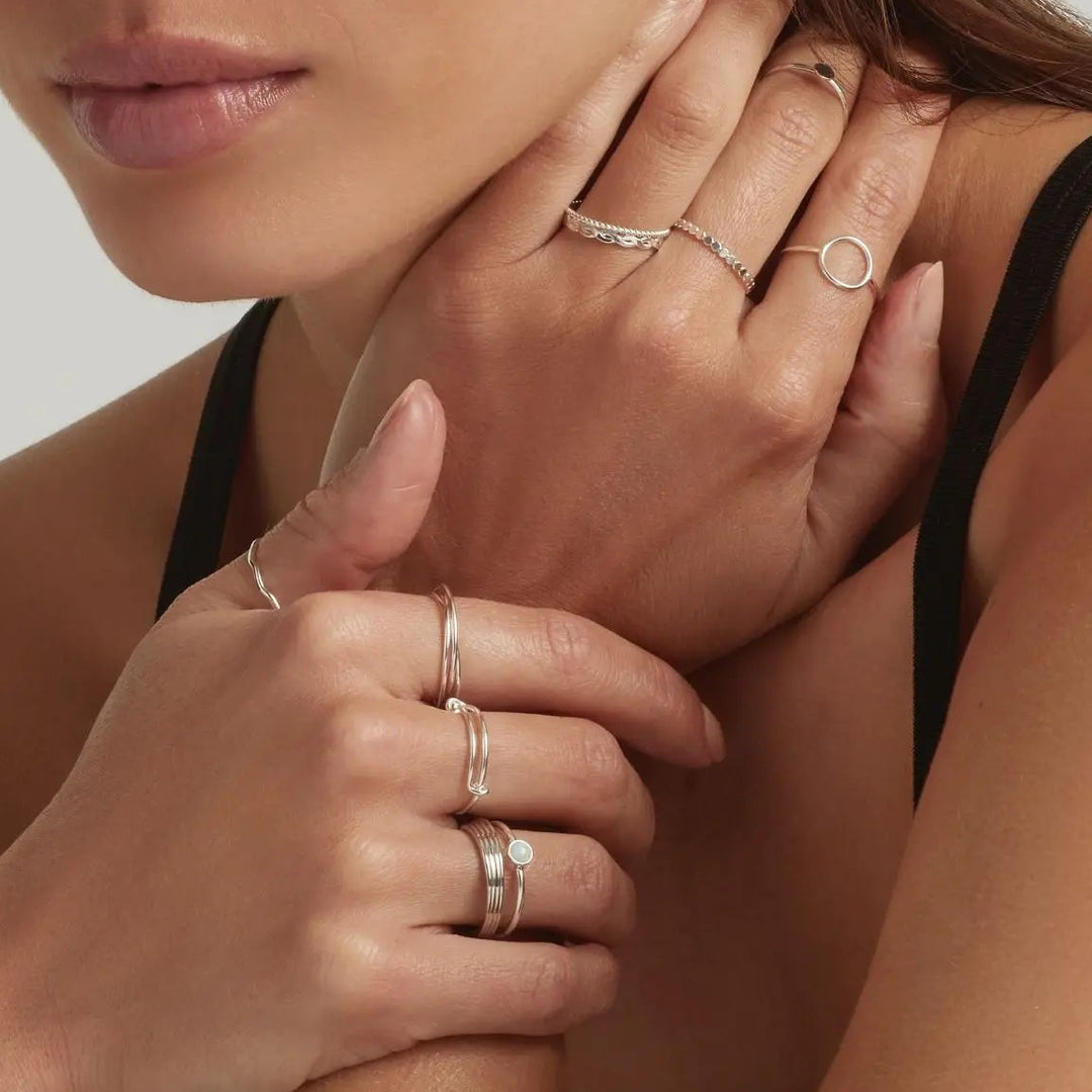 Close-up of a woman's hands wearing multiple minimalist 925 sterling silver stacking rings 