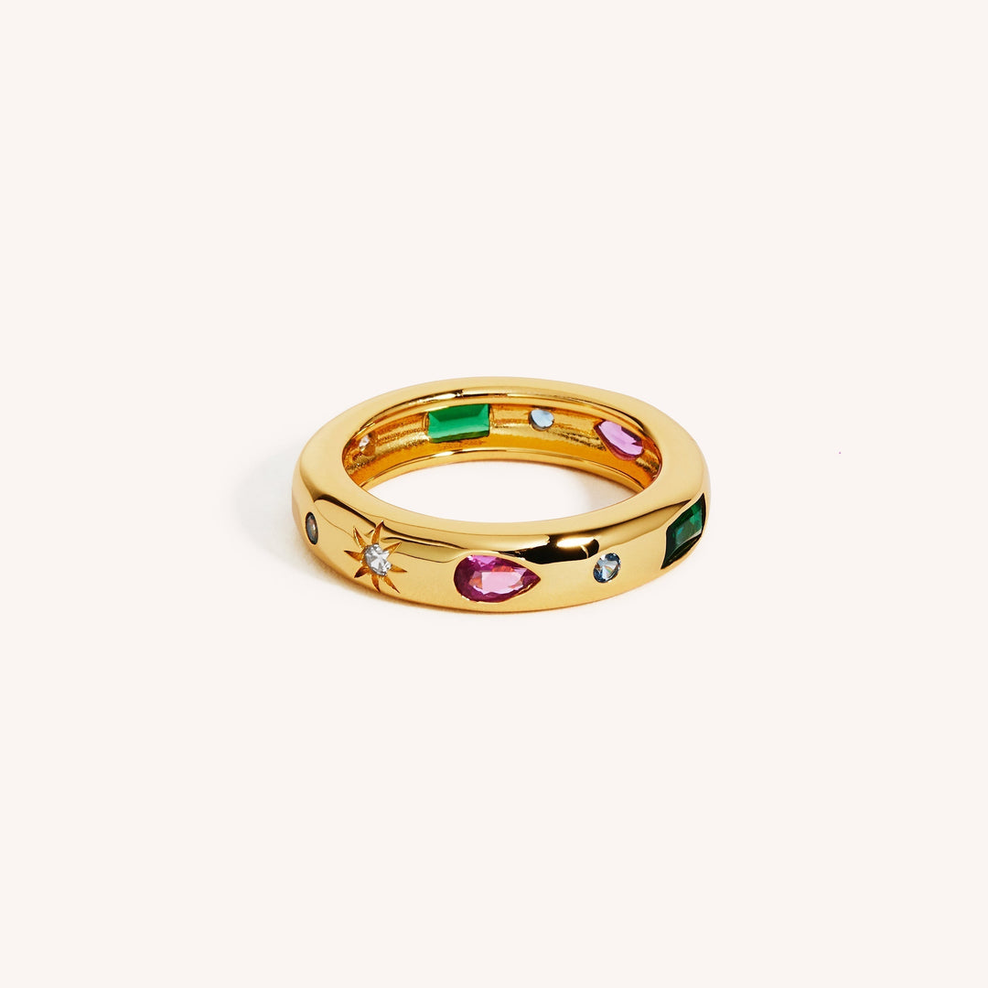 An 18K gold vermeil ring with a gold band featuring geometric emerald and pink zircon shapes, and white zircon accents.