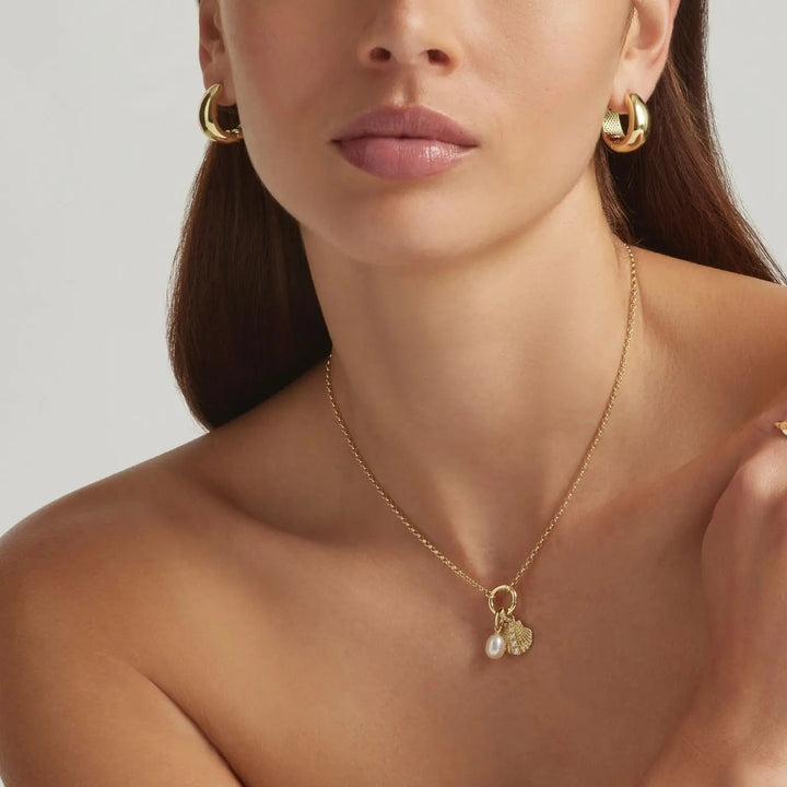 Model wearing gold vermeil earrings and charmedit necklace close up